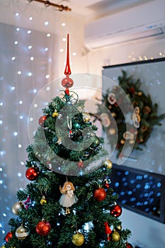 Christmas tree with a red top decorated with colorful toys and balls stands in the room