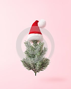 Christmas tree in Santa hat on pink background in minimal style.