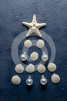 Christmas tree from sea shells and starfish on blue background, top view