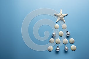 Christmas tree from sea shells and starfish on blue background, top view