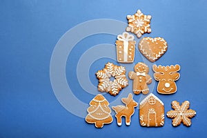 Christmas tree shape made of delicious gingerbread cookies on blue background, flat lay. Space for text