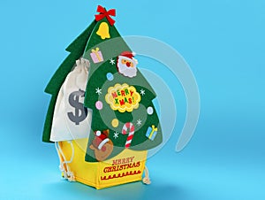 a Christmas tree shape package with US money bags on blue background with copy space