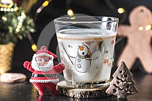 Christmas tree shaped cookie and a glass of milk for Santa Claus, close up, indoor. Holiday concept