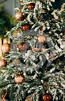 Christmas tree with shiny baubles in living room.