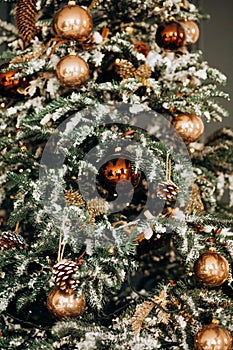 Christmas tree with shiny baubles in living room. Branches of Christmas trees with golds and brown toys and garland. Winter