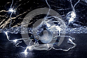 Christmas tree, silver, sparkling ball, garlands and tinsel, on a dark background.