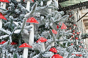 Christmas tree in the snow decorated with festive garlands and fly agarics. New Year decorations
