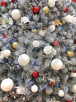 Christmas tree with snowy branches and red and white balls toys, festive background decor for New Year eve is greeting card.