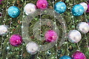 Christmas tree sparkles with garland lights, Decorated with silver, blue and pink ornaments