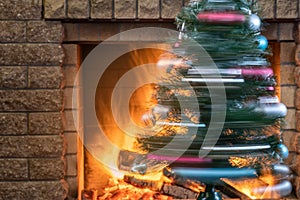A Christmas tree is spinning against the background of a burning fireplace in a country house