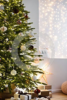 Christmas tree in stylish winter holiday interior with stars, lights, gifts and decoration. Xmas interior design template