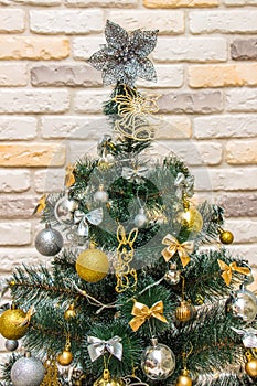 Christmas tree-topper in shape of a star or bow decorating xmas fir tree with the gold and silver baubles, multi-colored bows,