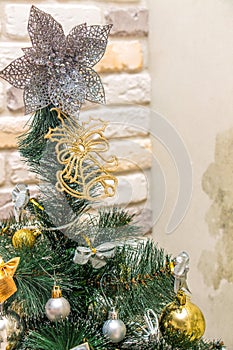 Christmas tree-topper in shape of a star or bow decorating xmas fir tree with the gold and silver baubles, multi-colored bows,