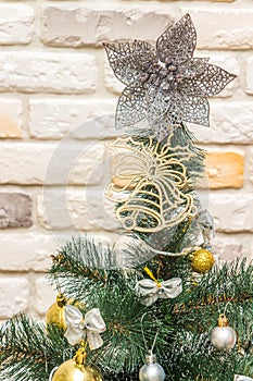 Christmas tree-topper in shape of a star or bow decorating xmas fir tree with the gold and silver baubles, multi-colored bows,