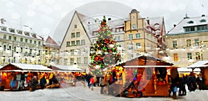 Christmas tree on town square in  old town of Tallinn and holiday marketplace  with walking people under snowflakes