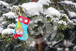 A Christmas tree toy is hanging on a winter tree covered with snow in the forest