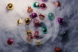 Christmas tree toys, colorful glass balls scattered on white snow, top view.