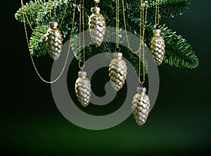 Christmas tree toys fir cones hanging on golden chains on fir branches on dark background