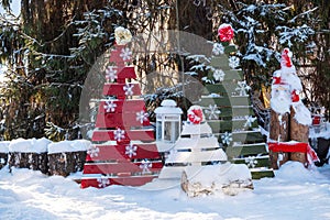 Christmas tree with toys and sled in the city Park. Decorated tree outside with lights covered with snow. A clear winter