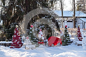 Christmas tree with toys and sled in the city Park. Decorated tree outside with lights covered with snow. A clear winter