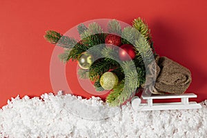 Christmas tree with toys on a sleigh in decorative snow. Christmas story on paper red background