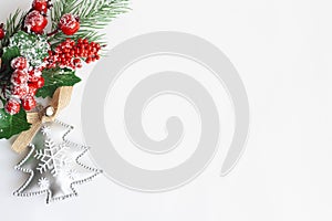 Christmas tree twig with red berries and holly leaves and Christmas tree toy on a white background, copy space