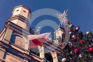 Christmas tree under clear, blue sky with church and Polish flag in the background