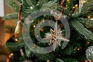 Christmas tree with vintage star and baubles with golden lights close up. Modern decorated christmas tree branches with stylish