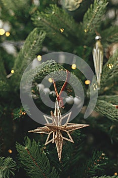 Christmas tree with vintage star and baubles with golden lights close up. Modern decorated christmas tree branches with stylish