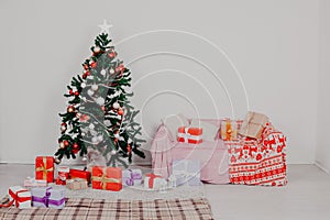 Christmas tree in a white room with Christmas decorations and gifts toys