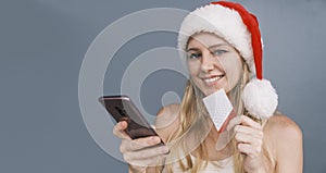 Christmas trip. Portrait of woman looking at camera with credit card and phone in hands, buying ticket online, wearing