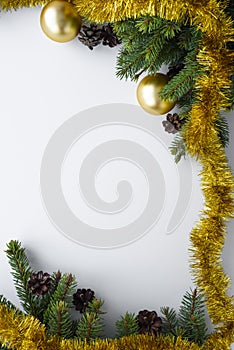 Christmas vertical greeting card with copy space. Ornament decorations such as gold baubles, tinsel, evergreen tree branches and