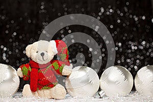 Christmas view of teddy bear in red green sweater and Christmas hat and four silver evening balls