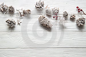 Christmas white background. Rustic garland with fir cones, red berries and snowy stars. Copy space below