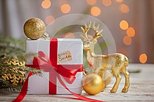 Christmas white box or present with golden balls and deer for secret santa on wooden table