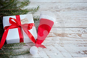 Christmas white box or present with red ribbon for secret santa with santa hat on wooden table