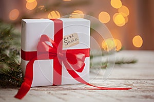 Christmas white box or present with red ribbon for secret santa on wooden table