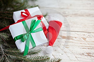 Christmas white boxes or presentes with santa hat on white wooden table
