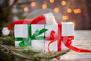 Christmas white boxes or presentes with santa hat on white wooden table