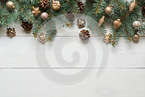 Christmas white frame of golden baubles and evegreen fir tree on wooden board. Top view.