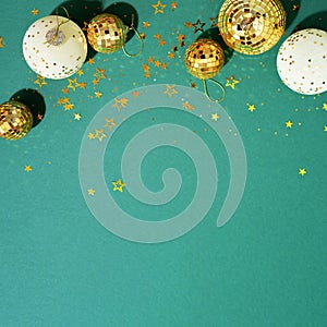 Christmas white and gold decorations, mirror disco balls, star sparkles over green background. Flat lay, top view. Minimal New