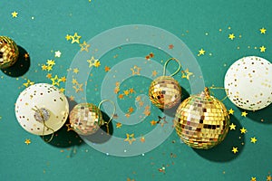 Christmas white and gold decorations, mirror disco balls, star sparkles over green background. Flat lay, top view. Minimal New