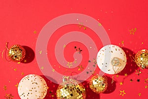 Christmas white and gold decorations, mirror disco balls, star sparkles over red background. Flat lay, top view. Minimal New year