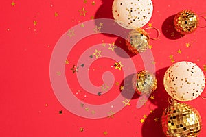 Christmas white and gold decorations, mirror disco balls, star sparkles over red background. Flat lay, top view. Minimal New year
