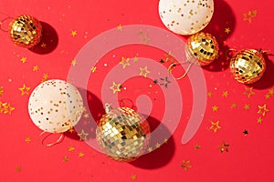 Christmas white and gold decorations, mirror disco balls, star sparkles over red background. Flat lay, top view. Minimal New year