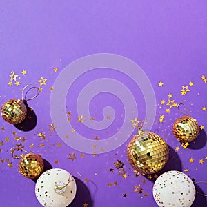 Christmas white and gold decorations, mirror disco balls, star sparkles over violet background. Flat lay, top view. Minimal New