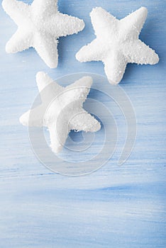 Christmas white snow stars on light blue wood background with space for text.