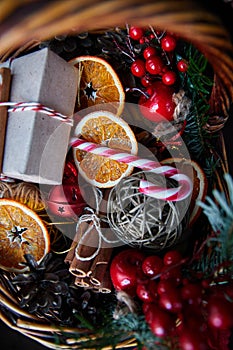 Christmas wicker basket with striped candy canes, dried sliced oranges, cones and gifts