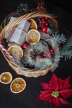 Christmas wicker basket with striped candy canes, dried sliced oranges, cones and gifts