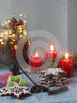 Christmas window. Candles, garlands, Christmas decoration, gingerbread cookie. Close-up, it is raining. Vertical orientation